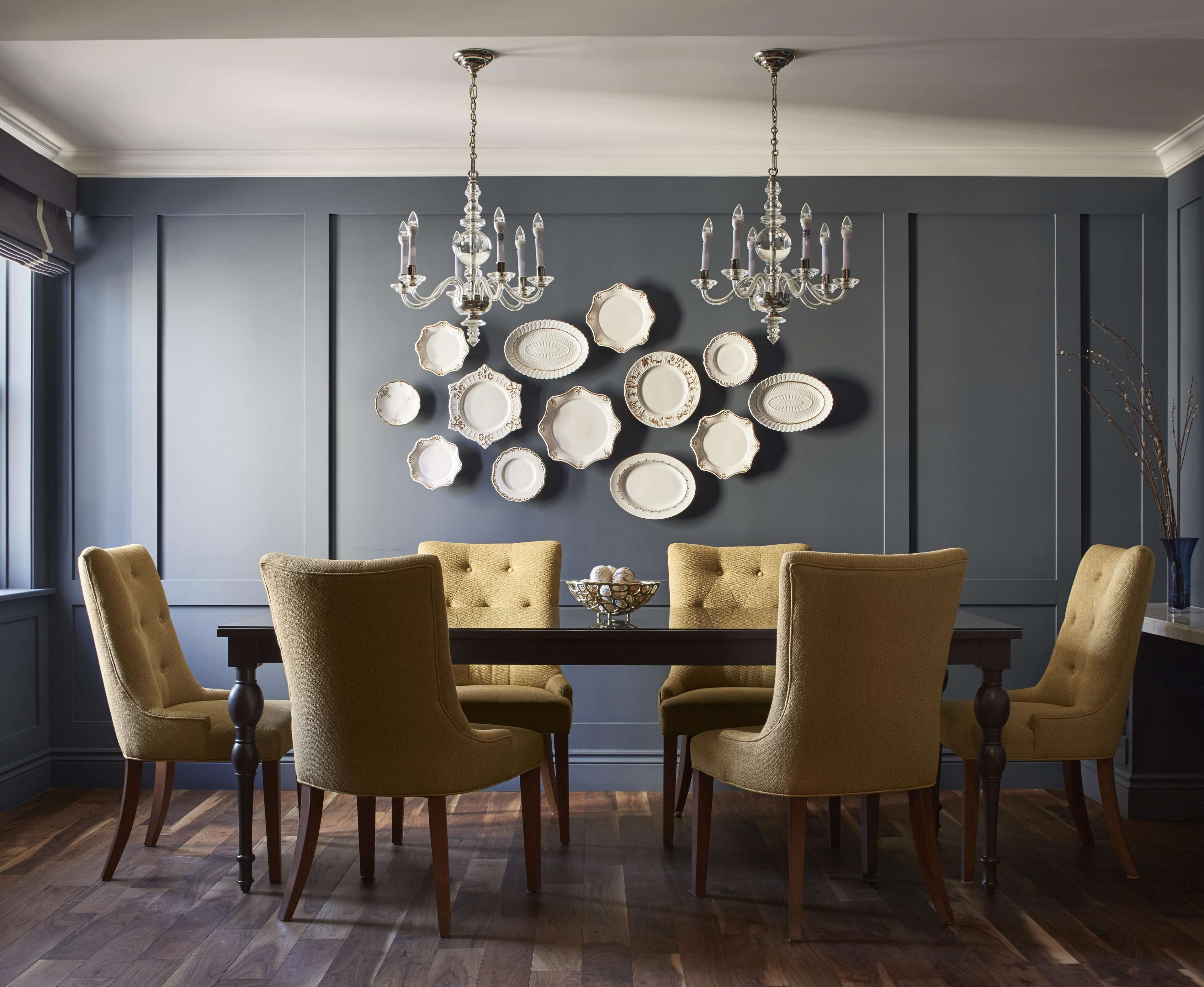 Une salle à manger avec un mur bleu foncé, un lustre et une table entourée de six chaises.
