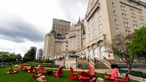 A historic building with a central courtyard featuring red Adirondack chairs and a fire pit.