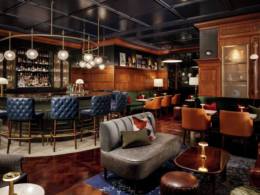 Un'area bar con bancone, diversi sgabelli e una zona salotto con divani e poltrone.