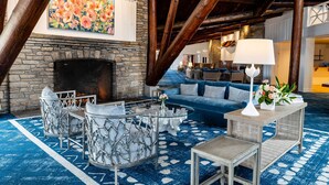 A cozy lounge area with a stone fireplace, blue patterned carpet, and modern furniture.