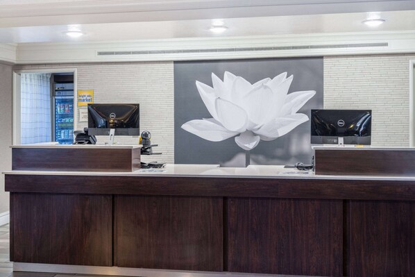 A reception desk with a large floral artwork, a refrigerator, and a flat-screen TV.