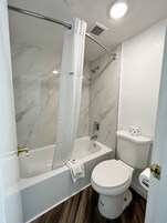 Un baño con bañera, inodoro y ducha.