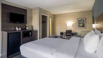 Ein Hotelzimmer mit einem Bett, einem an der Wand montierten Fernseher, einem Schreibtisch mit einer Lampe und einer Mikrowelle.