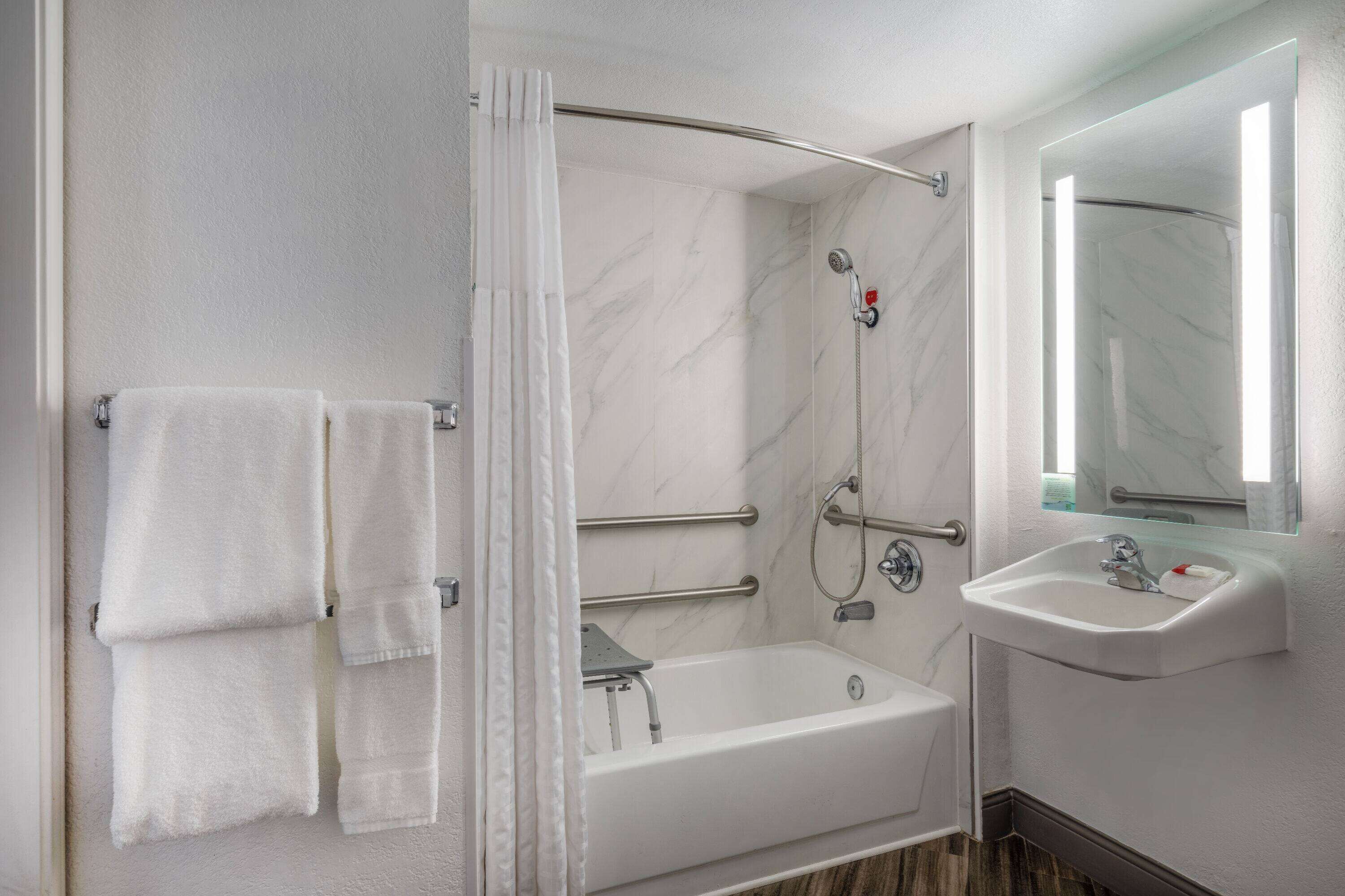 A modern bathroom with a bathtub, shower, and sink.
