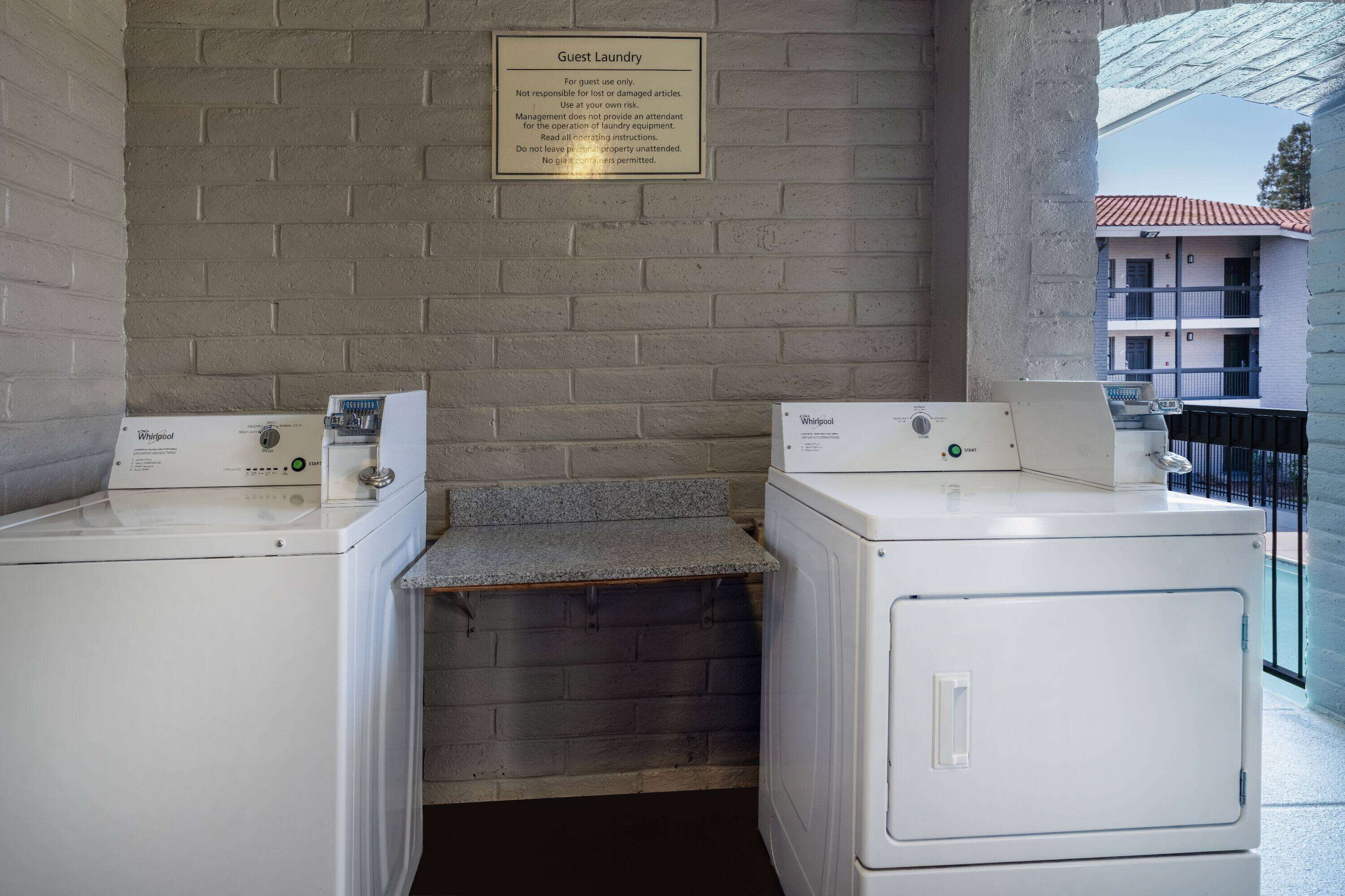 A laundry area with two Whirlpool washers and a sign above them.