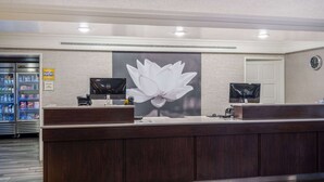 Un comptoir d’accueil orné d’une grande œuvre d’art représentant une fleur de lotus, deux écrans et un réfrigérateur contenant des boissons.