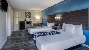 Une chambre d’hôtel avec deux lits, un bureau, une télévision et un minibar.