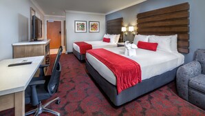 Une chambre d’hôtel avec deux lits, un bureau et une chaise.