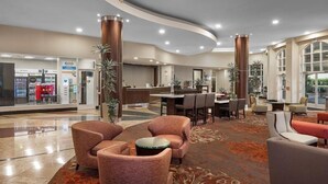 Un hall d’hôtel comprenant un comptoir d’accueil, un espace salon et des distributeurs automatiques.