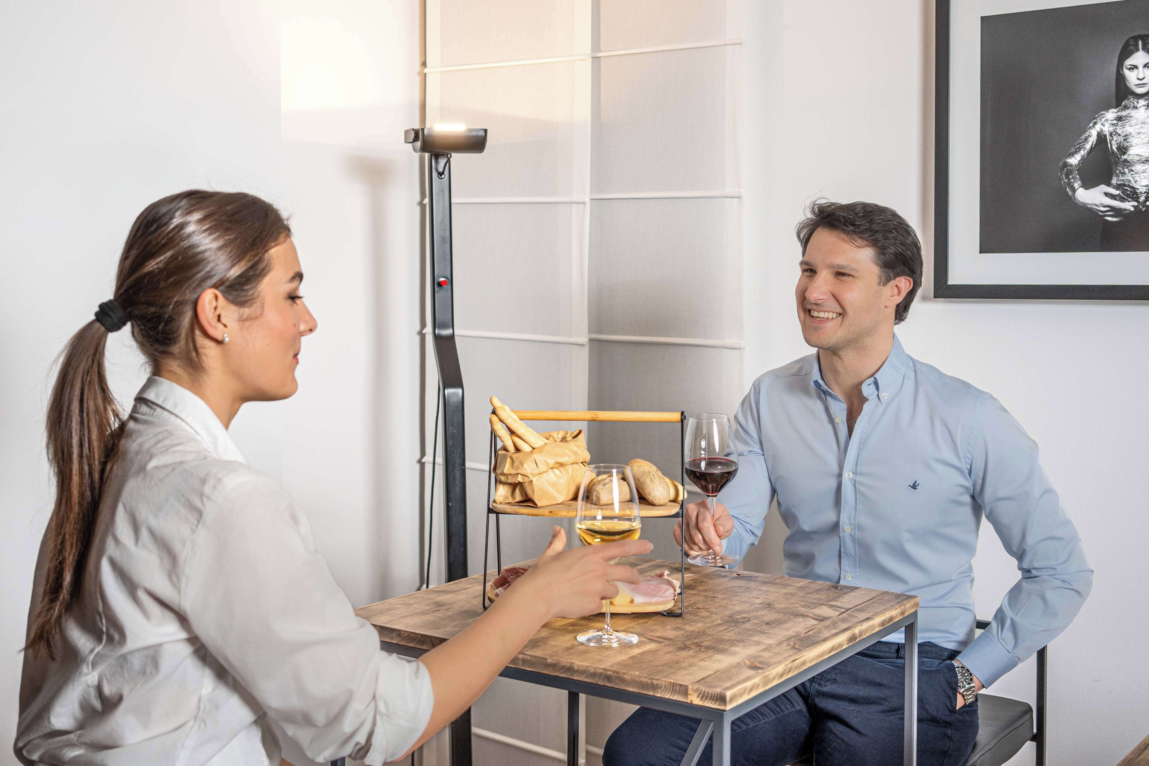Une table à manger avec un panier à pain, un verre de vin blanc et un sandwich.