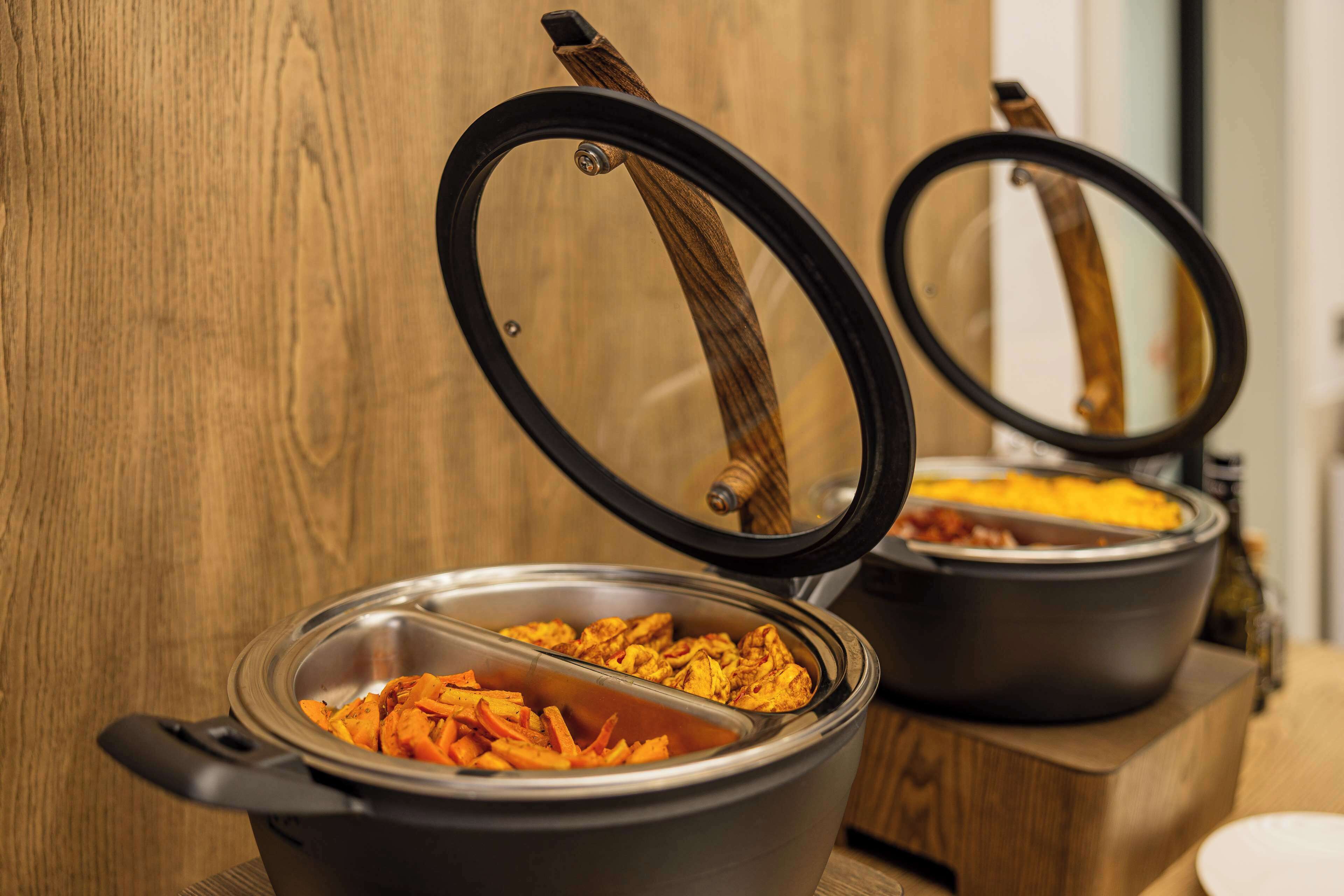 Two covered food dispensers with lids on a wooden surface.