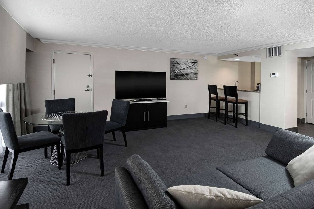A modern living room with a gray sofa, a round coffee table, and a flat-screen TV.