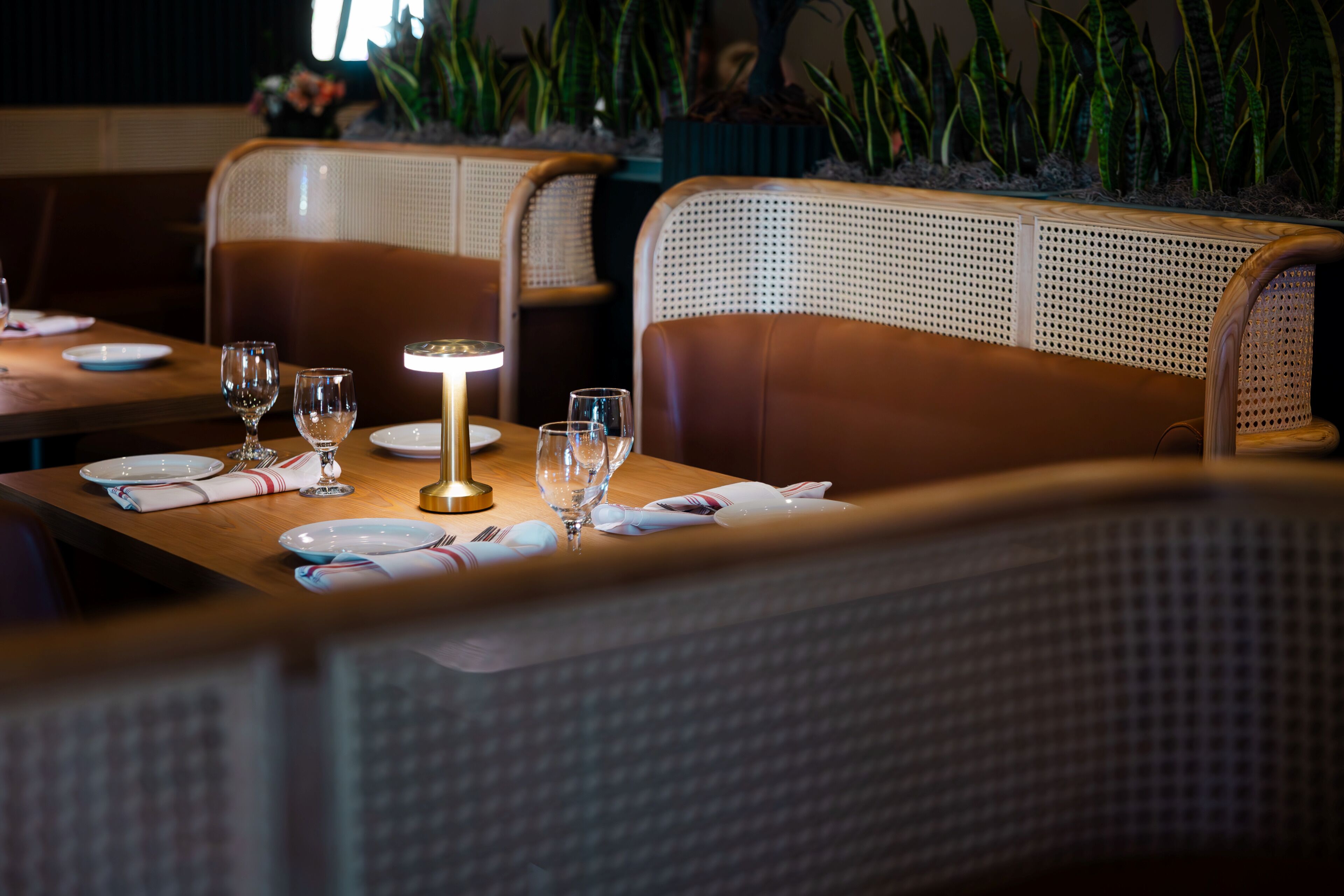 L’intérieur d’un restaurant avec des tables en bois, des chaises en osier et une atmosphère chaleureuse.