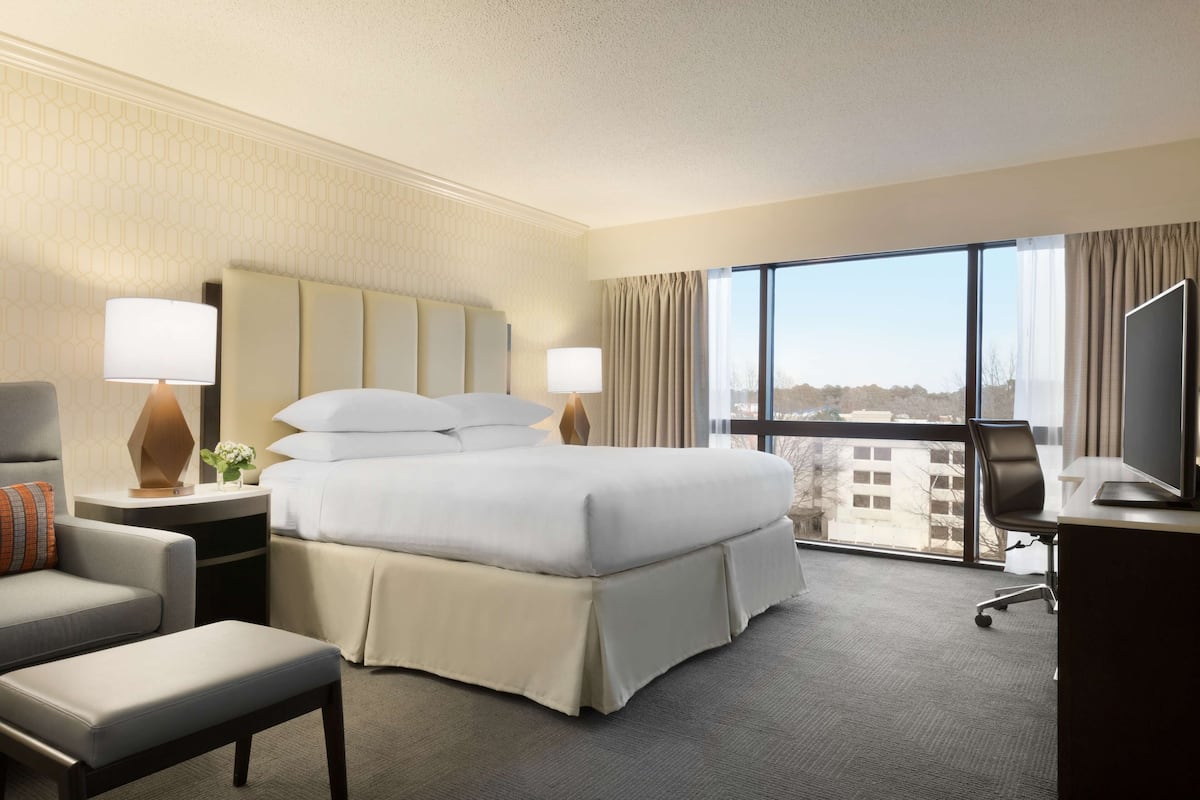 A hotel room with a large bed, a desk with a computer, a chair, and a TV.