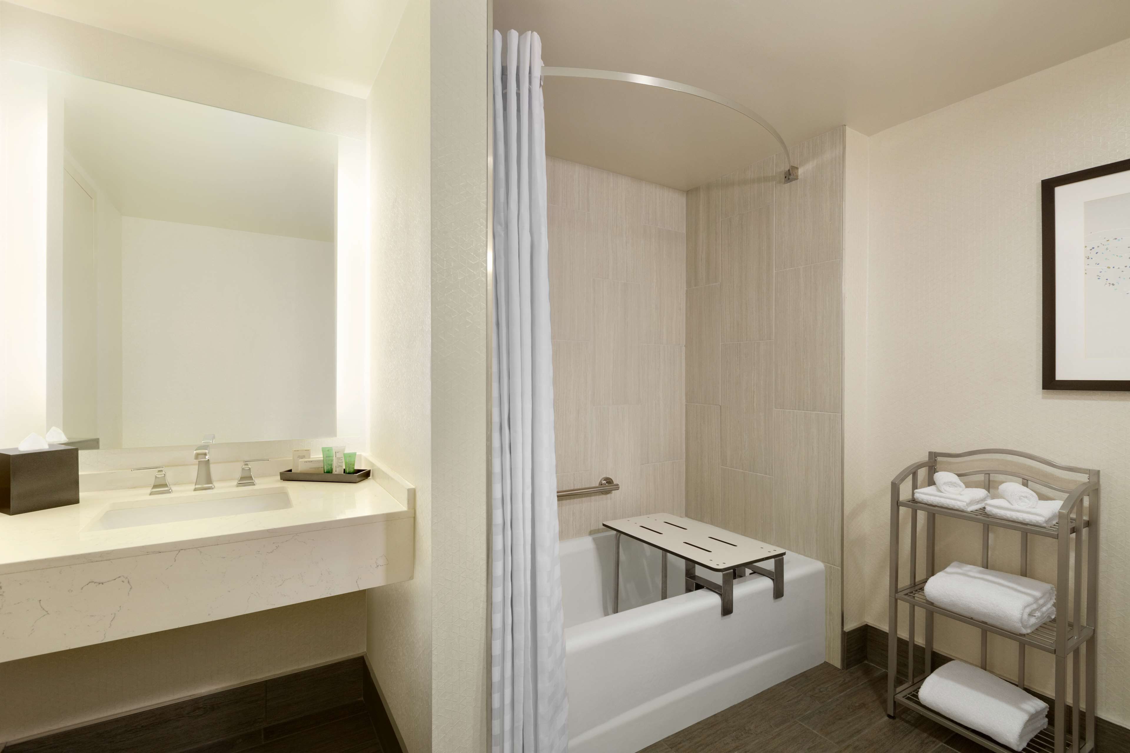 A bathroom with a white bathtub, a vanity with a mirror, and a towel rack.