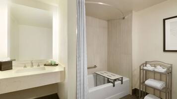 A bathroom with a white bathtub, a vanity with a mirror, and a towel rack.
