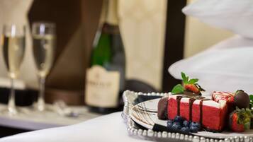 A dessert tray with a red cheesecake, strawberries, and blueberries, accompanied by champagne glasses and a bottle.