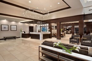 Experience the hotel's elegant lobby, featuring a reception desk, seating area, and dining space.