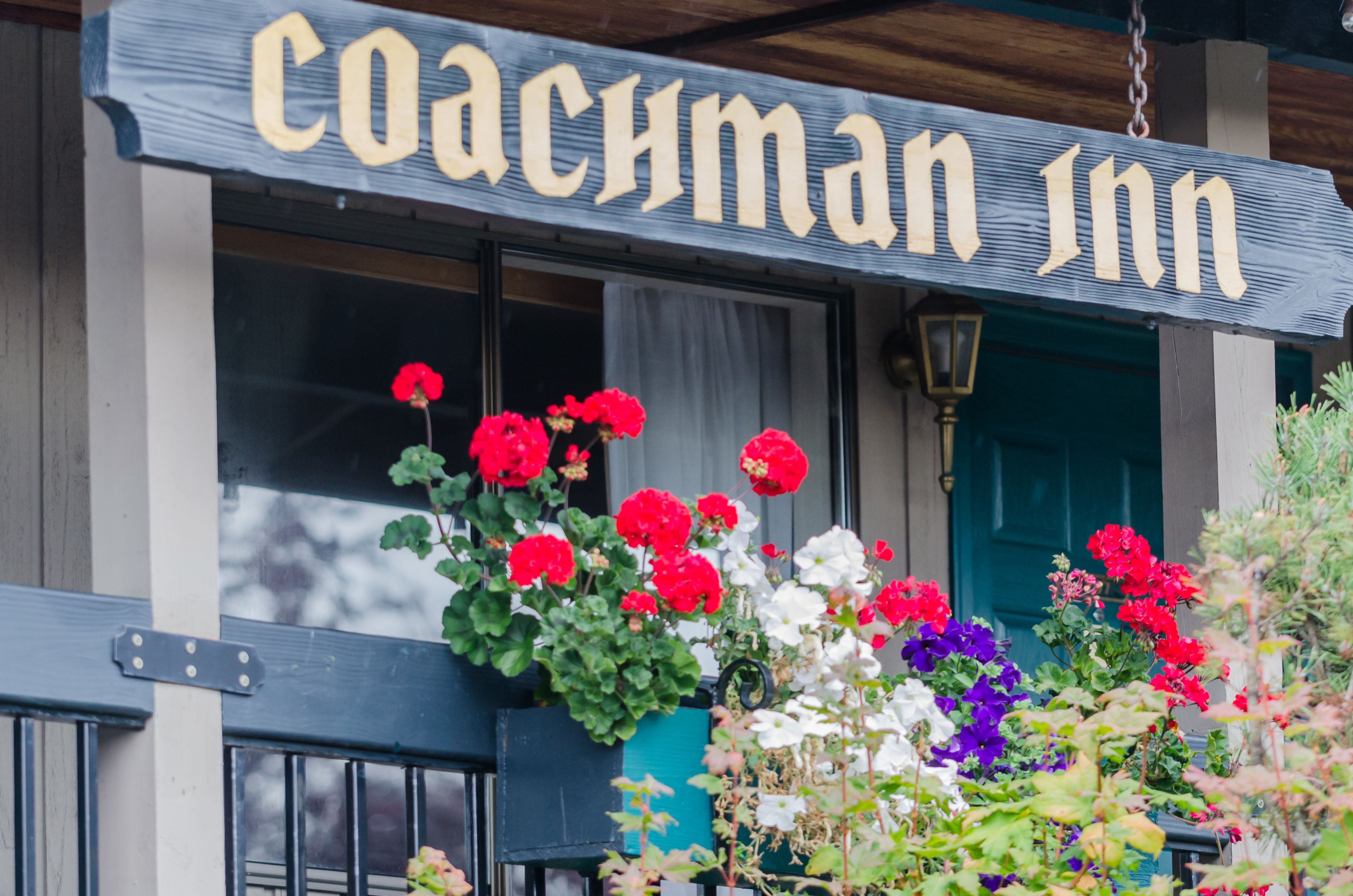 Een bord met 'Coachesman Inn', met een raam en een deur op de achtergrond.