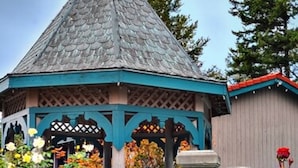 A gazebo with a conical roof, surrounded by a garden with various flowers and a street lamp. - Coachman Inn & Suites (Oak Harbor)