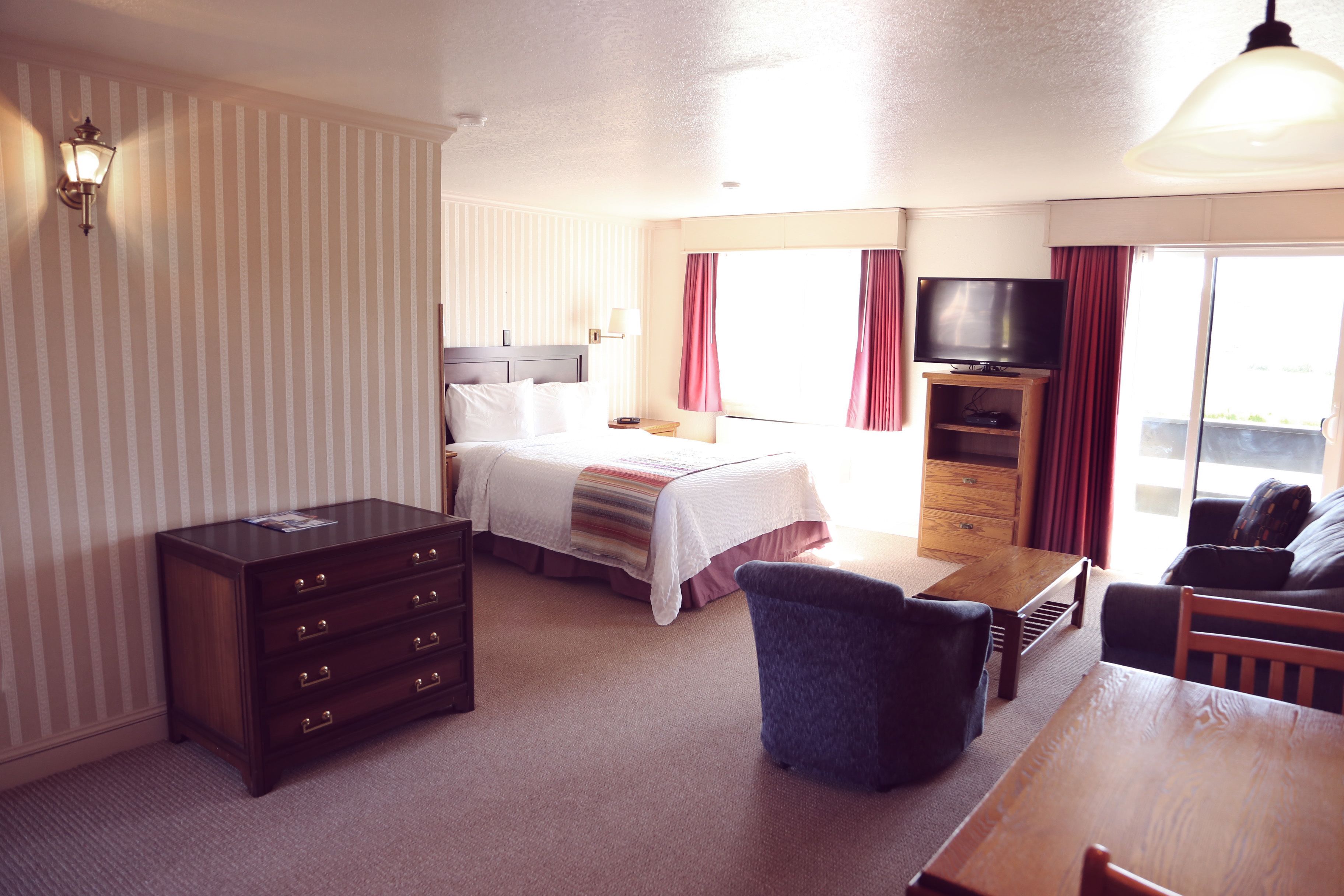 Ein Hotelzimmer mit Bett, Kommode, Fernseher, Esstisch und Stuhl.