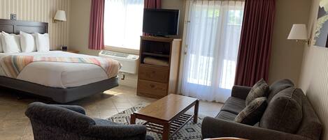 Ett hotellrum med en säng, en tv, en soffa, ett soffbord och ett tv-bord.