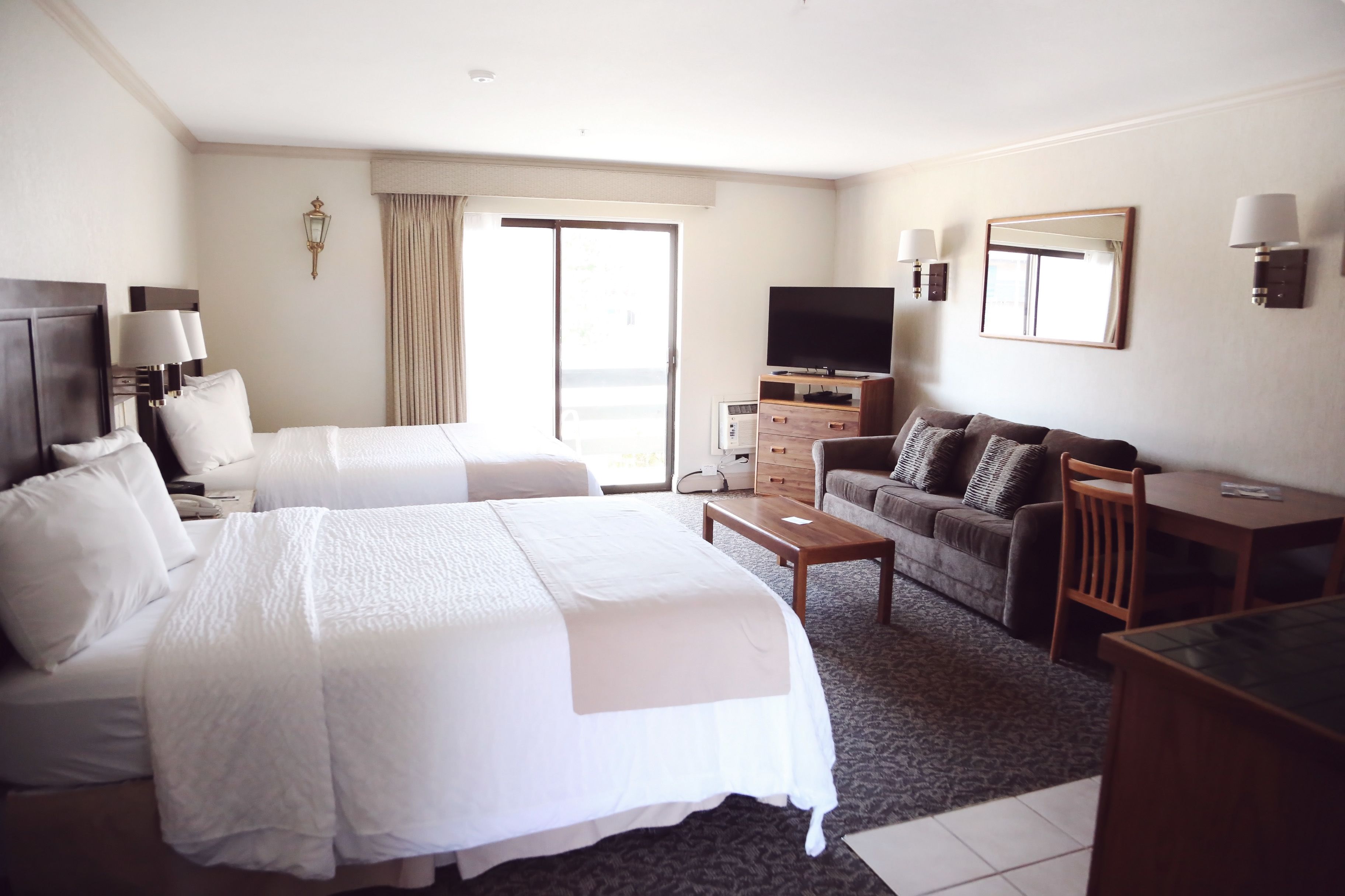 Habitación de hotel con dos camas, un sofá, un televisor y un escritorio.