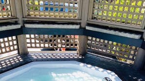 A hot tub with a metal ladder, surrounded by a wooden fence with lattice panels.