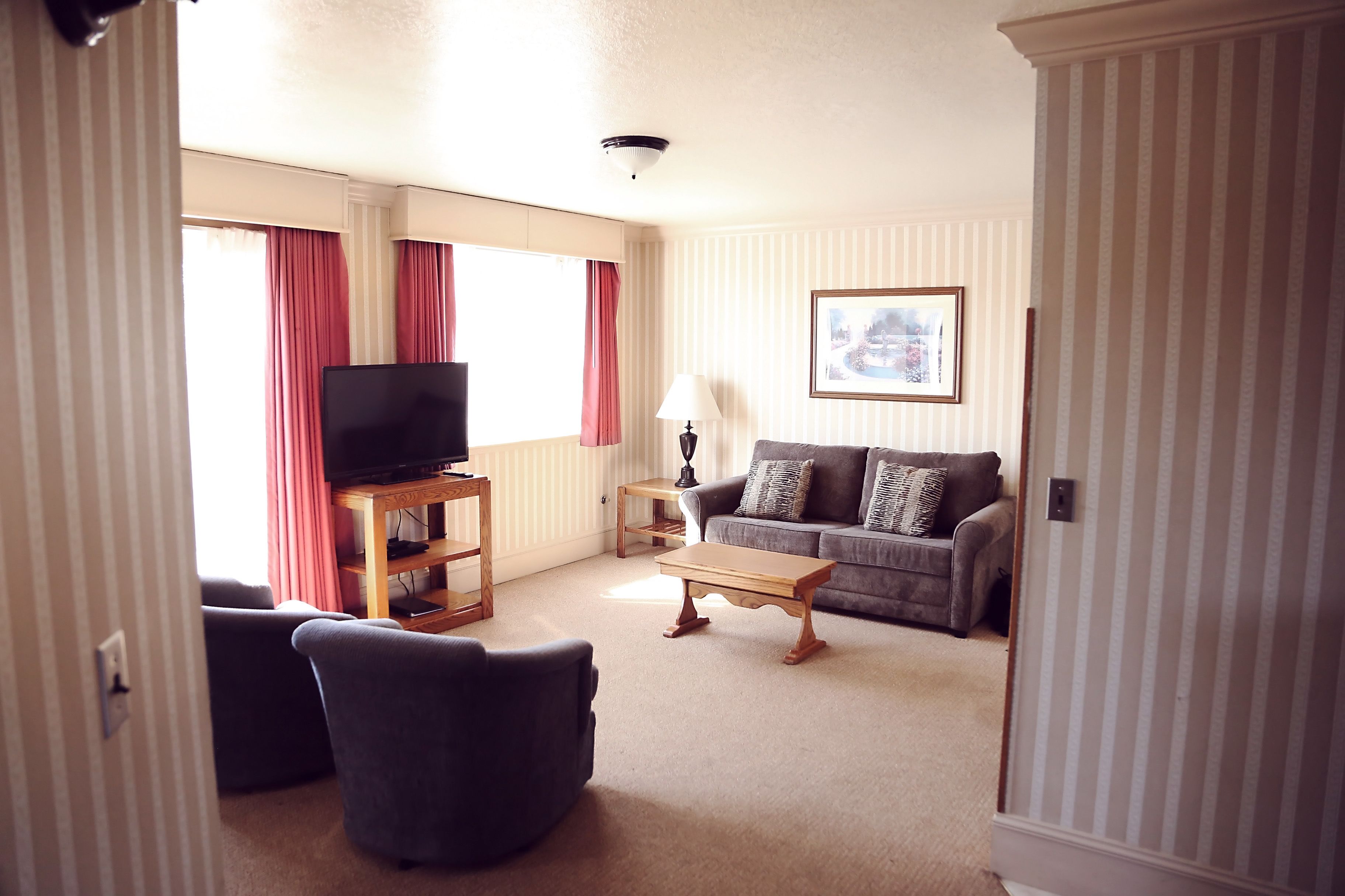 A living room with a television, sofa, armchair, and a small table.