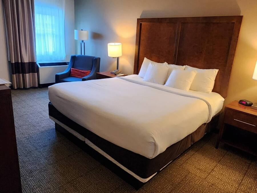 Ein Hotelzimmer mit einem großen Bett, einem Sessel, einem Schreibtisch und einer Lampe.
