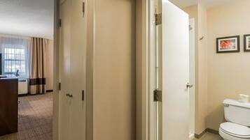 A hotel room with a bed, a desk, a bathroom with a toilet, and a shower.