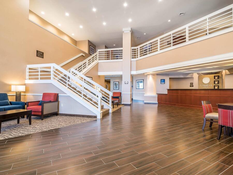 A spacious lobby with a staircase, seating area, and a reception desk.