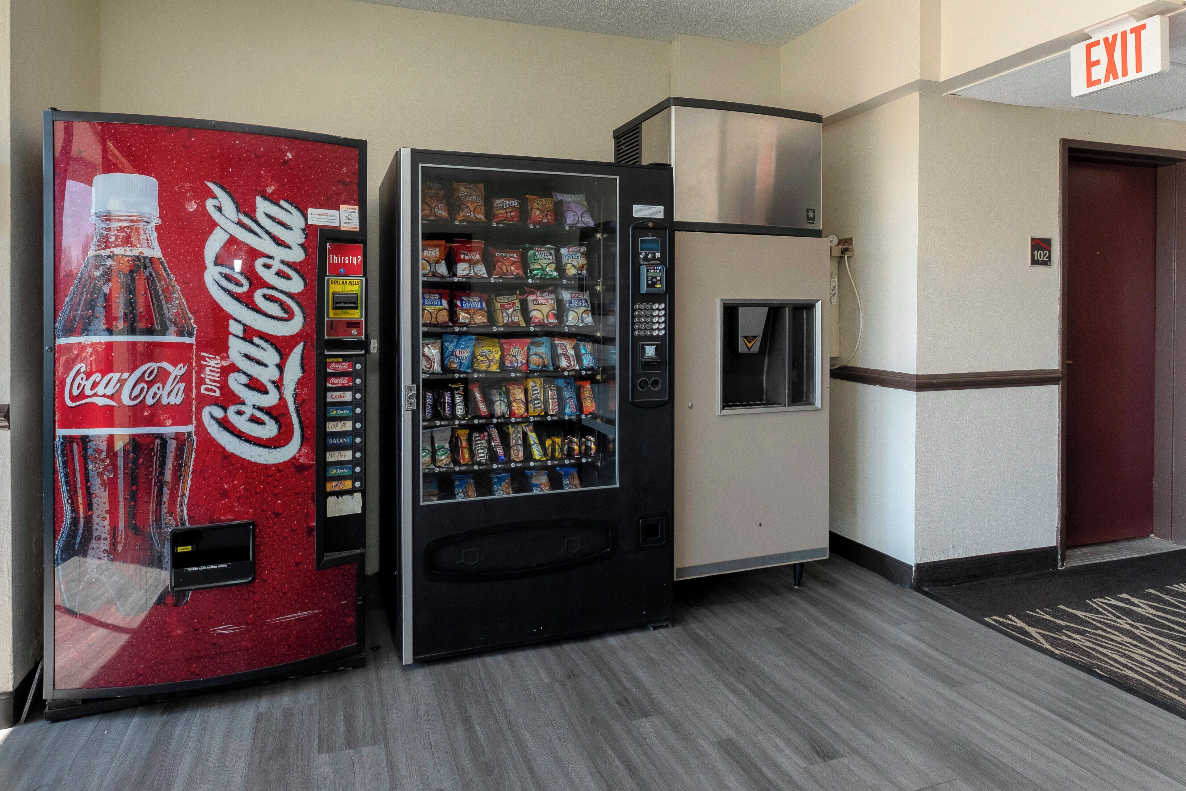 A vending machine with a Coca-Cola logo, a snack vending machine, and a refrigerator.
