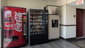 A vending machine with a Coca-Cola logo, a snack vending machine, and a refrigerator.