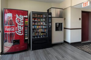 A vending machine with a Coca-Cola logo, a snack vending machine, and a refrigerator.