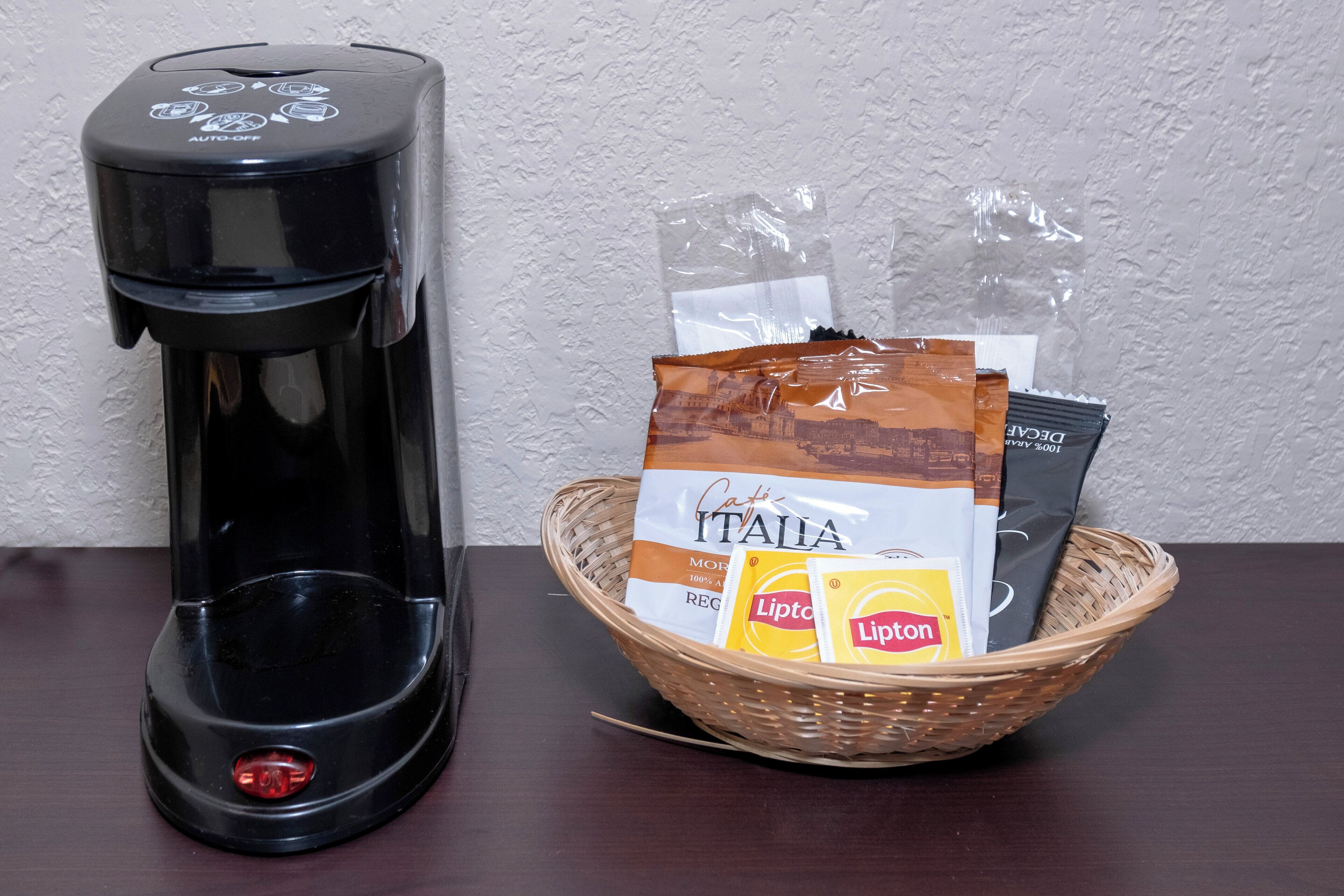 Una macchina da caffè e un cesto con capsule di caffè e una borsa con il logo.