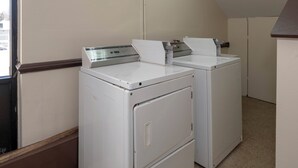 A laundry room with two stacked washers and dryers, a window, and a door.