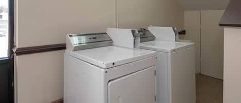 Une buanderie équipée de deux machines à laver et deux sèche-linge superposés, d’une fenêtre et d’une porte.