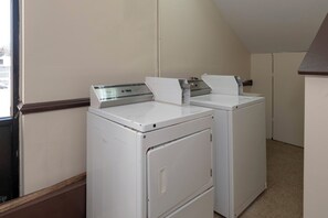 A laundry room with two stacked washers and dryers, a window, and a door.