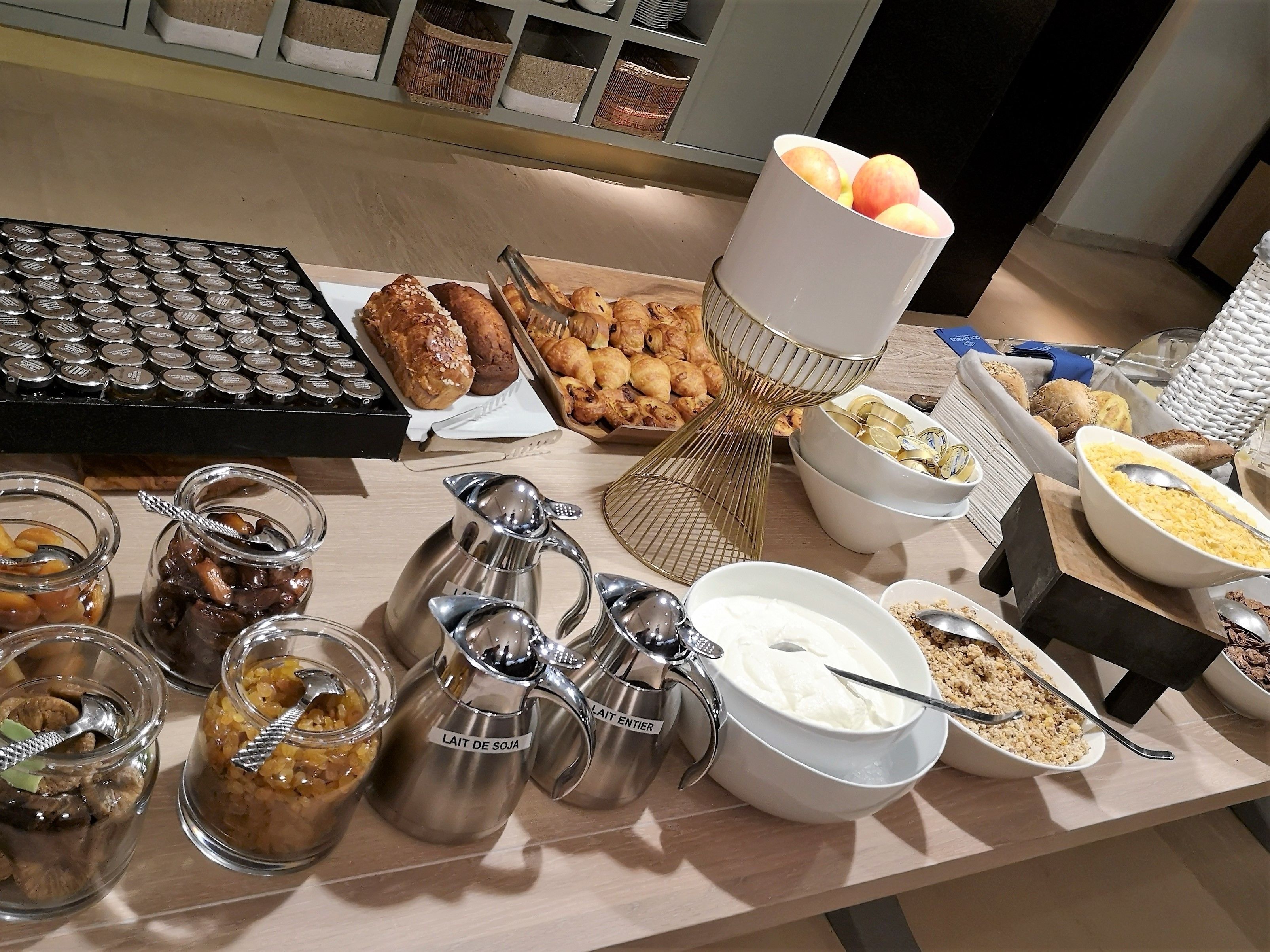 A buffet table with various food items, including pastries, bread, and condiments.