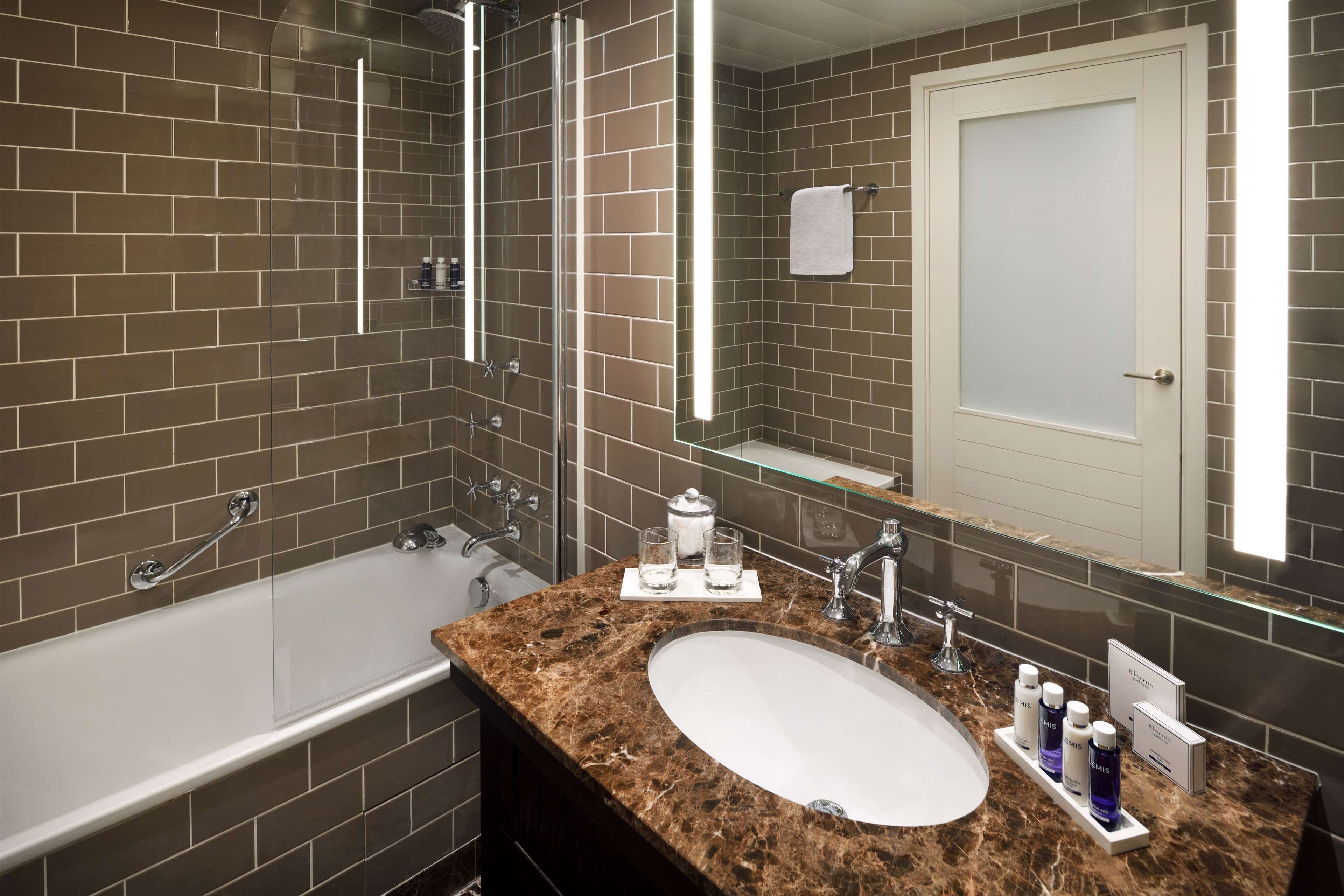 A modern bathroom with a bathtub, a sink, and a large mirror.