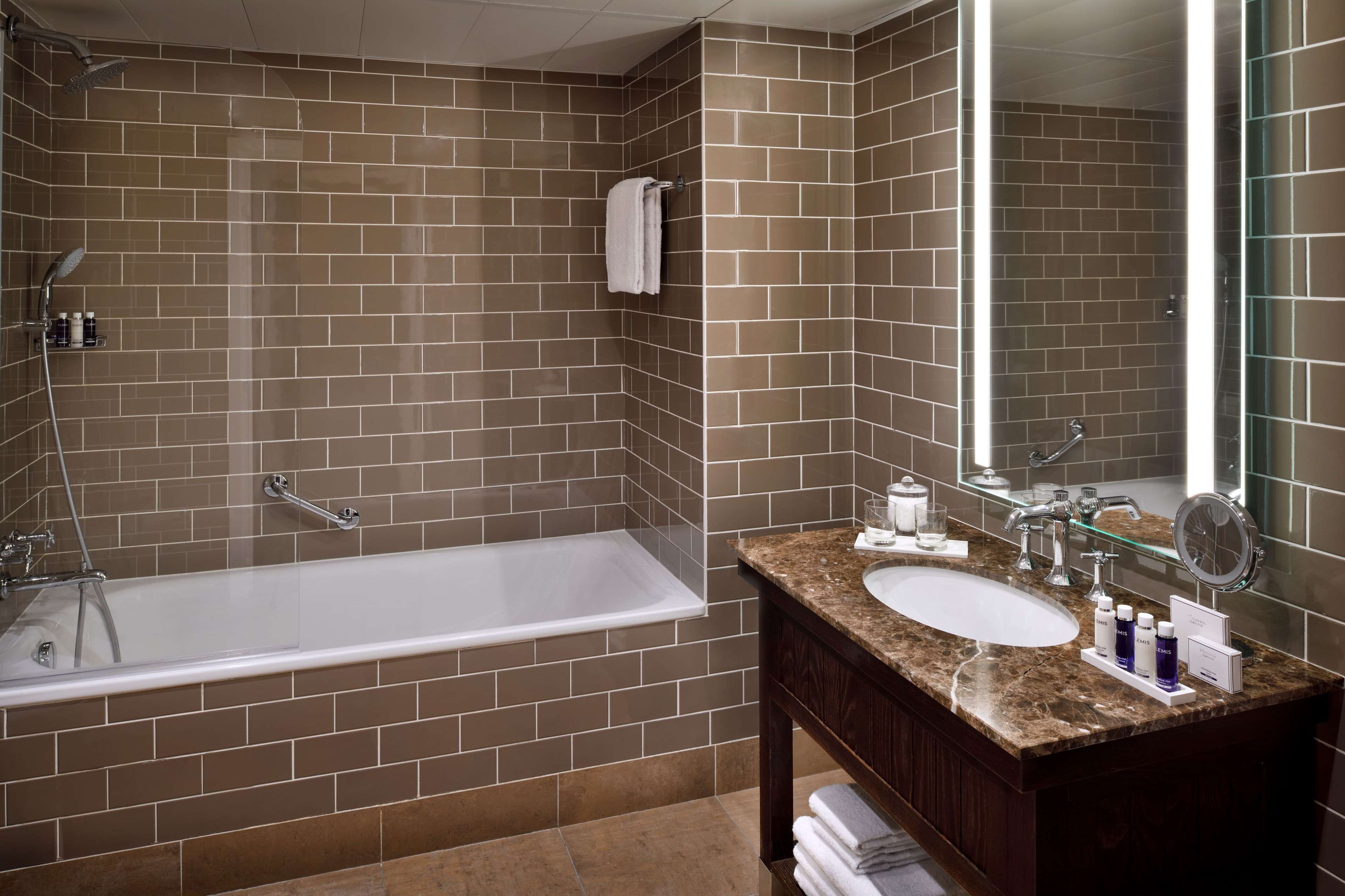 Une salle de bain moderne avec une baignoire, deux lavabos et un grand miroir.