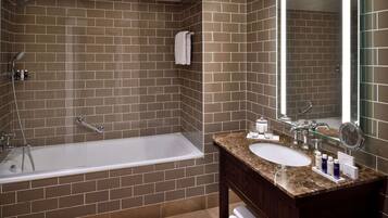 A modern bathroom with a bathtub, two sinks, and a large mirror.