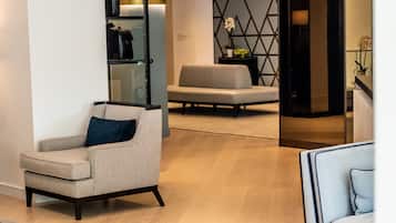 A modern hotel lobby with a seating area, a reception desk, and a wall-mounted luggage rack.