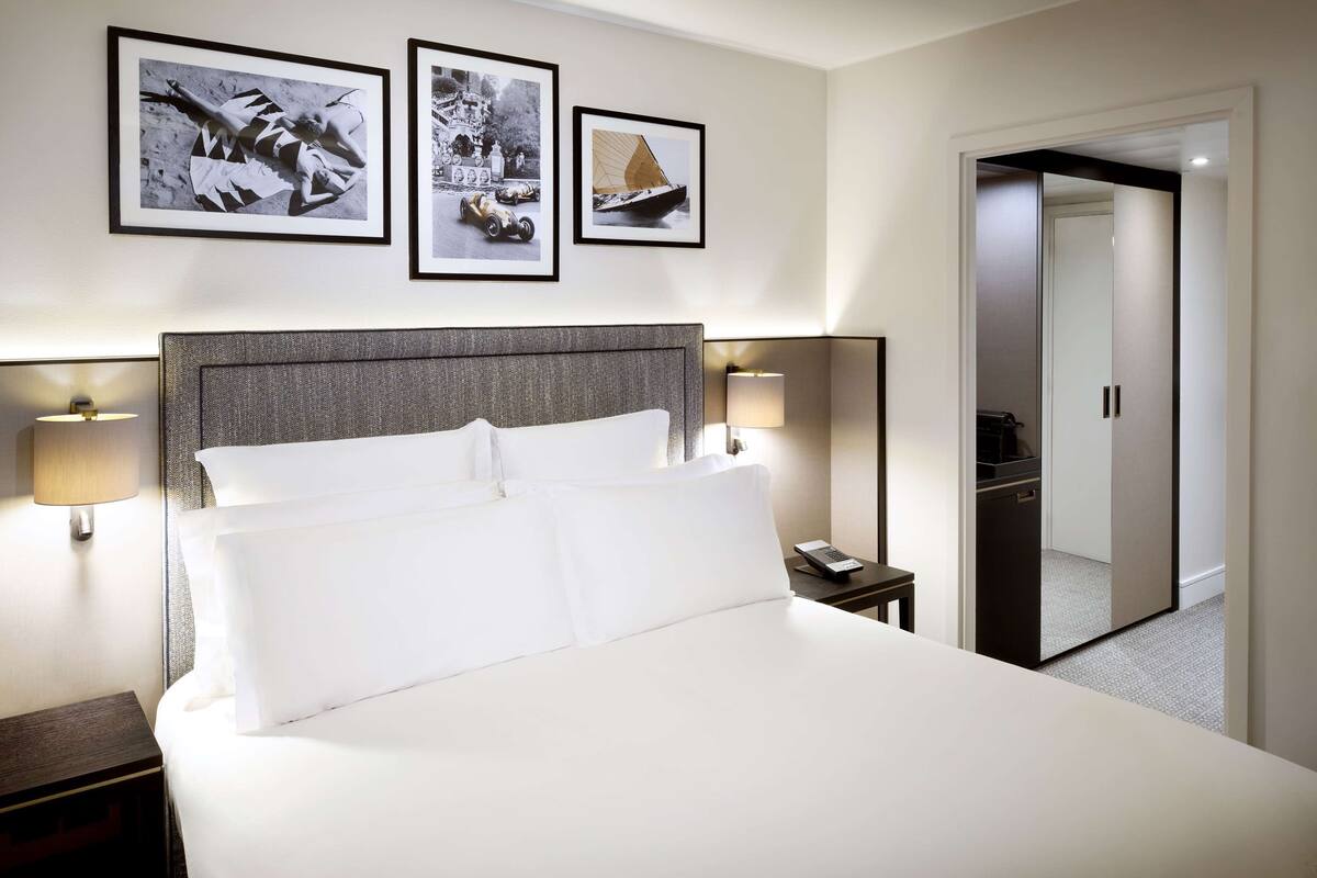 Ett hotellrum med en stor säng, två sänglampor och tre inramade tavlor på väggen.