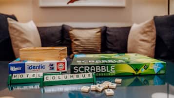 Un juego de Scrabble sobre una mesa de vidrio con fichas que deletrean "HOTEL" y "COLUMBUS" frente a un sofá con cojines.