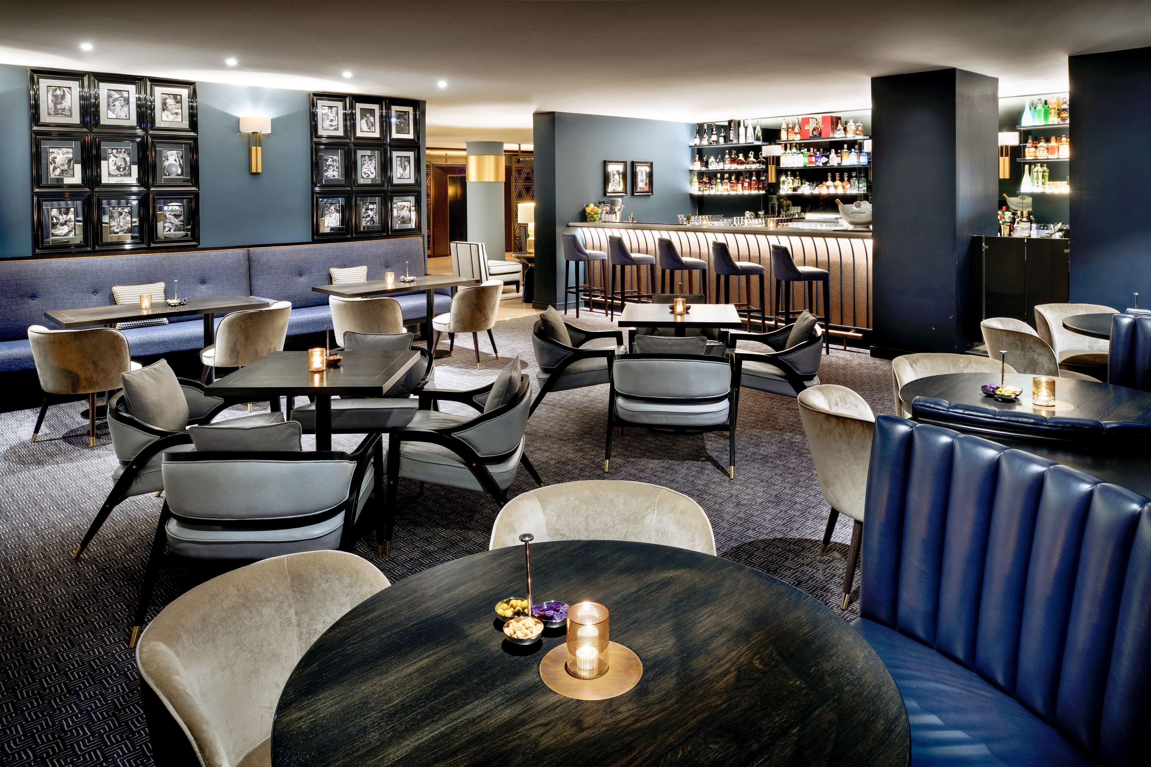 Zona de bar moderna con asientos, barra y una pared decorada con fotografías enmarcadas.