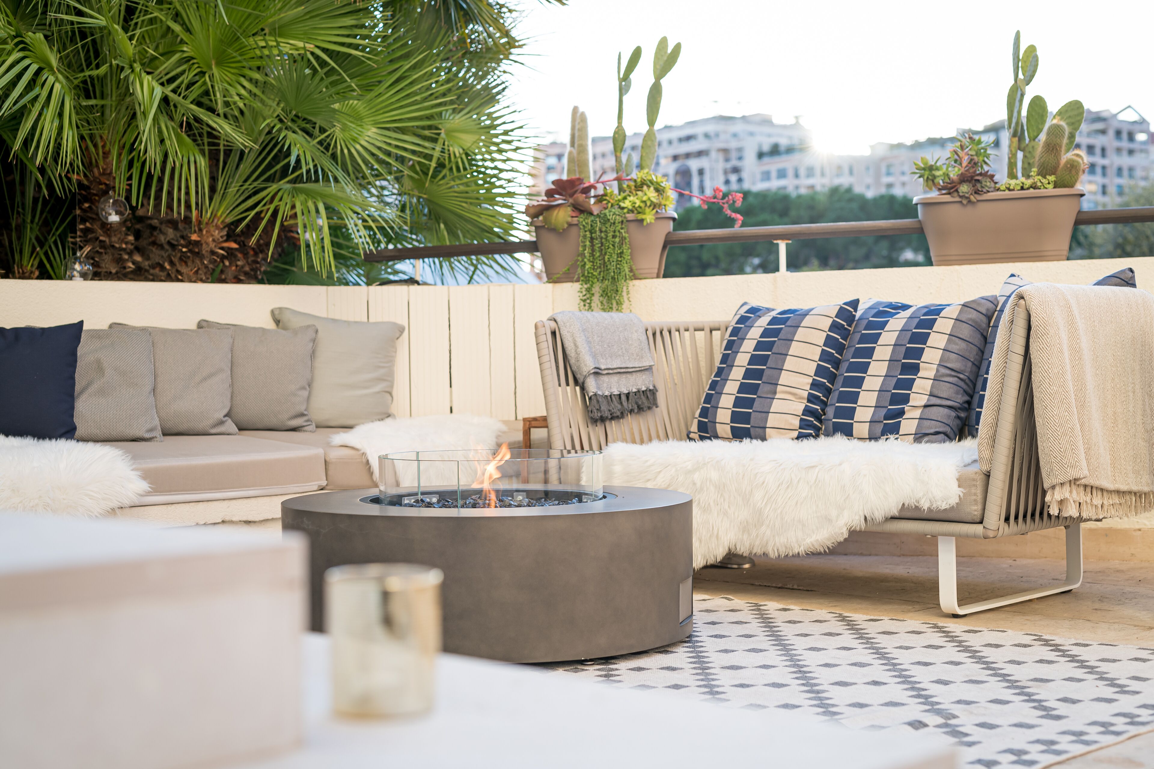 A rooftop terrace with a fire pit, seating area, and potted plants.
