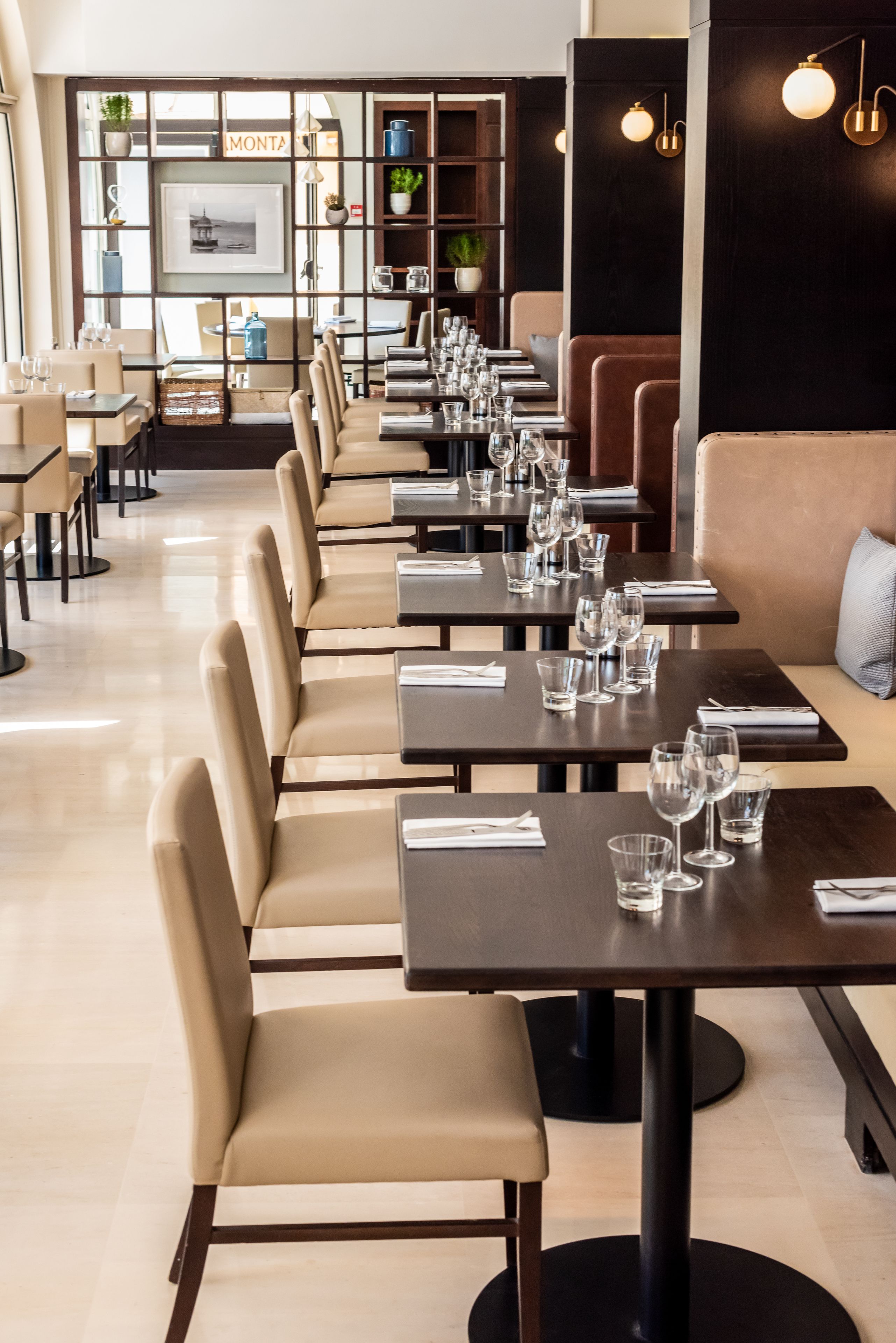 Un restaurante con mesas largas, cabinas, una zona de bar y una barra con menú.
