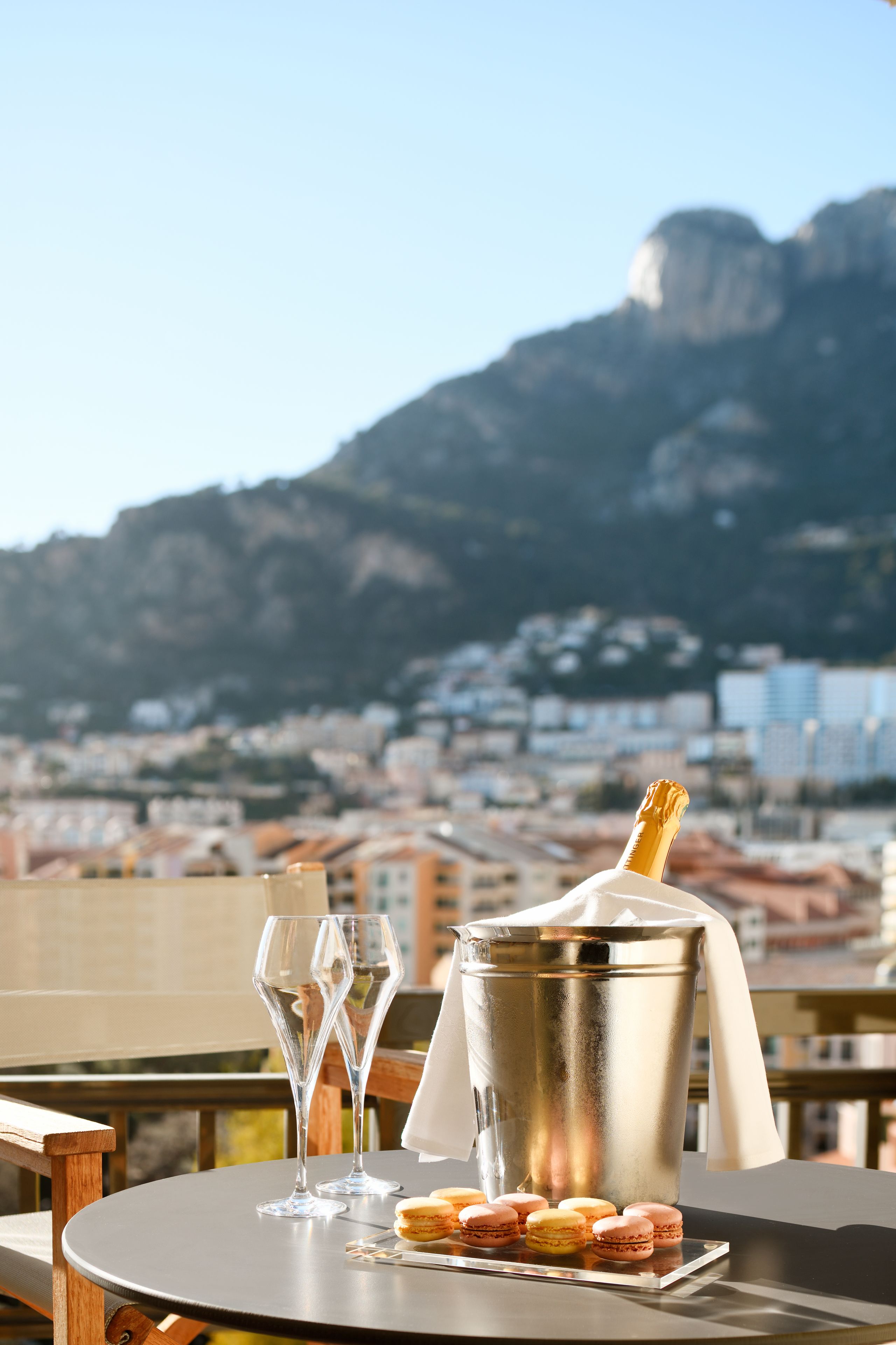 A table with a champagne bucket, two glasses, and macarons.